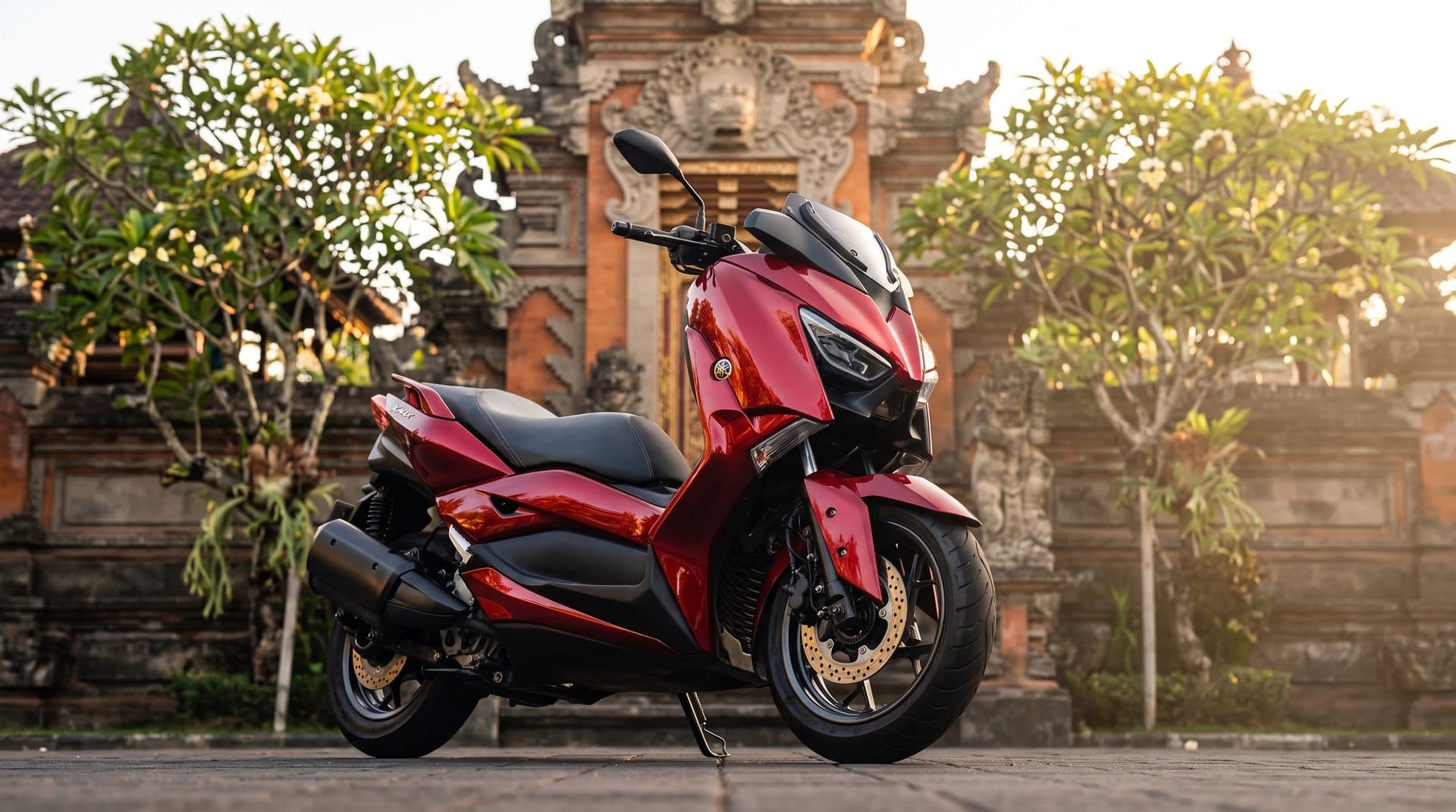 Кэнди-красный Yamaha Xmax перед балийскими воротами храма на закате